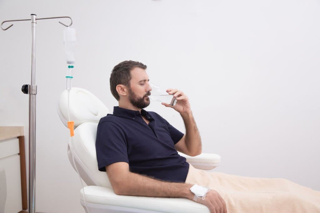 man drinking water with IV